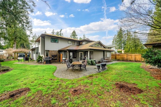 Rear view of house featuring a yard, a patio area, fence, and stone siding | Image 32
