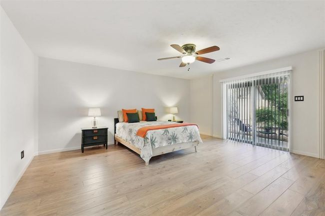 The spacious primary bedroom has a ceiling fan, luxury vinyl plank floors (2023) and access to one of the back patios through the sliding glass door. | Image 15