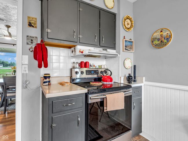 kitchen featuring tasteful backsplash, gray cabinetry, under cabinet range hood, and stainless steel electric range | Image 15