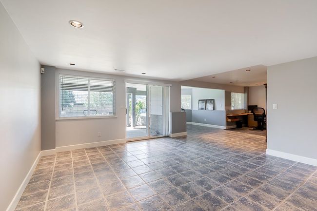 Unfurnished living room with stone tile floors, recessed lighting, and an office area | Image 28
