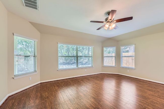 Primary bedroom featuring vaulted ceiling, wood finished floors, healthy amount of natural light, and a ceiling fan | Image 15