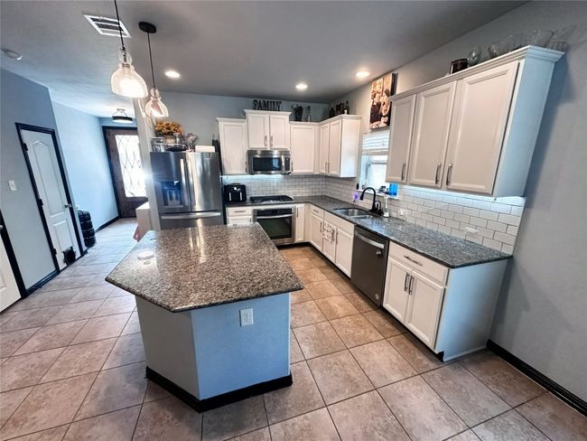 Kitchen featuring appliances with stainless steel finishes, plenty of natural light, a center island, decorative backsplash, and recessed lighting | Image 12