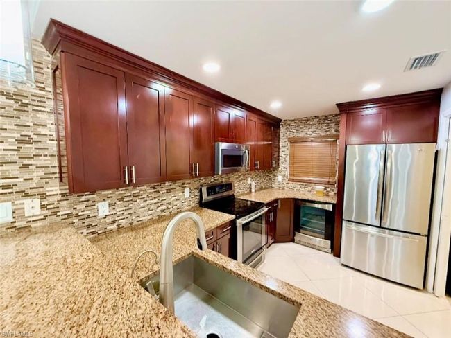 Kitchen featuring a sink, appliances with stainless steel finishes, wine cooler, visible vents, and dark brown cabinets | Image 14