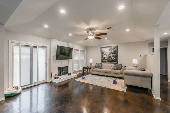 Unit 4904 Living room with ceiling fan, a wealth of natural light, and a fireplace | Image 23