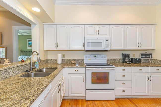 Kitchen with white appliances, white cabinets, ornamental molding, and a sink | Image 21