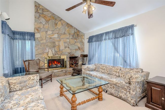 Living area with ceiling fan, vaulted ceiling, and carpet floors | Image 9