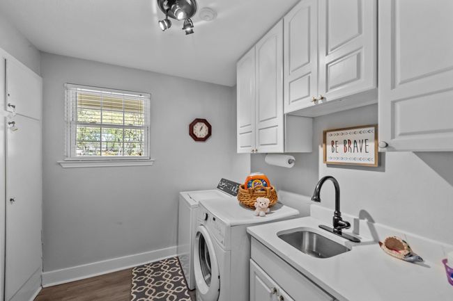 Laundry room featuring a sink, baseboards, washer and dryer, cabinet space, and dark wood-style flooring | Image 30