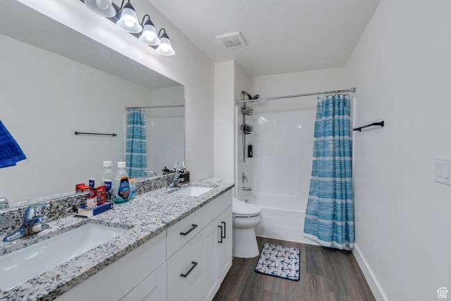 Bathroom with wood finished floors, shower / bath combination with curtain, and double vanity | Image 8