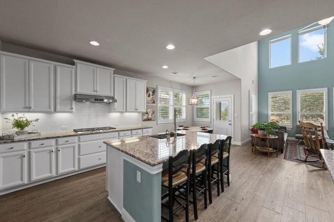 Kitchen featuring under cabinet range hood, light stone countertops, recessed lighting, healthy amount of natural light, and wood finished floors | Image 9