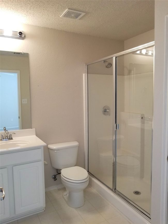 Full bathroom featuring a textured ceiling, a stall shower, vanity, and tile patterned floors | Image 16