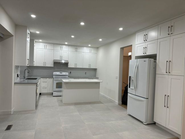 Kitchen featuring tasteful backsplash, white appliances, under cabinet range hood, visible vents, and a sink | Image 6