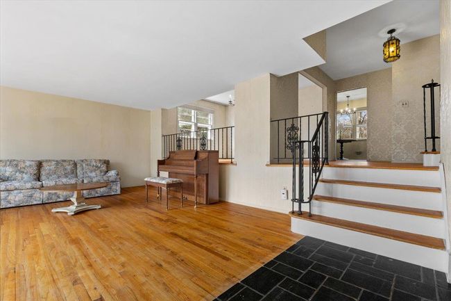 Living area with an inviting chandelier, wood finished floors, and stairs | Image 4