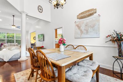 Dining area with ceiling fan with notable chandelier, decorative columns, dark hardwood / wood-style flooring, and a high ceiling | Image 3