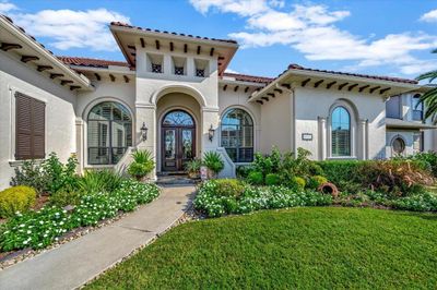 Elegant Mediterranean-style home with arched entryway, tiled roof, and well-manicured landscaping. The only one-story behind the gate in Seabrook Island | Image 1