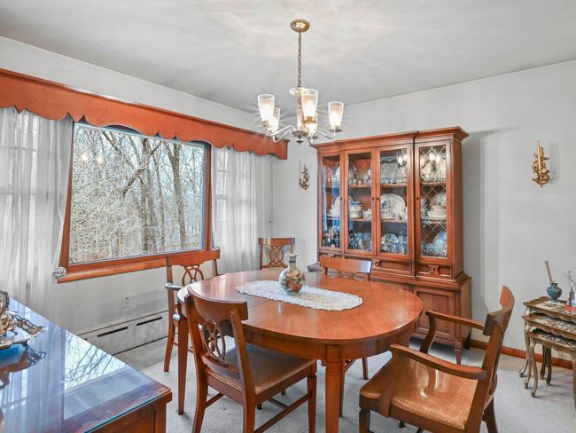 Dining area with light carpet, a baseboard radiator, and a notable chandelier | Image 18