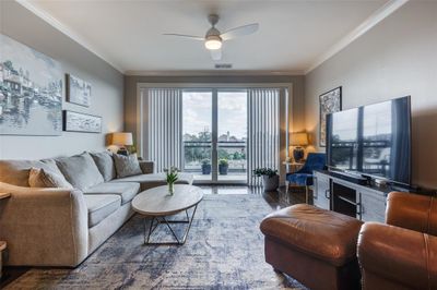 Living room featuring ceiling fan, crown molding, and dark wood-type flooring | Image 2