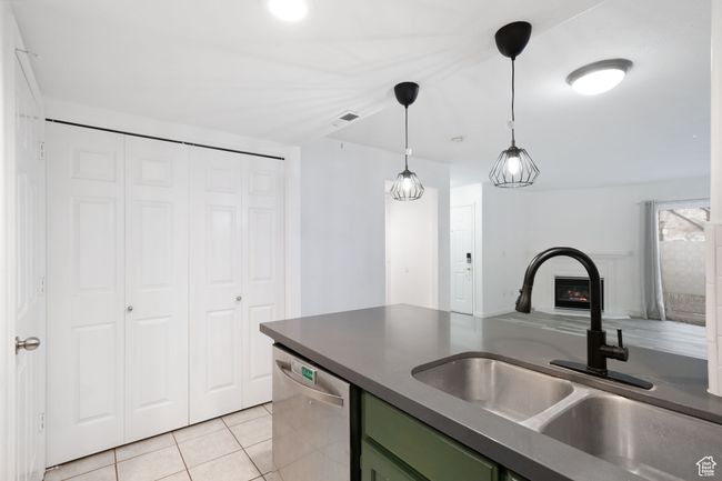 Kitchen with light tile patterned floors, green cabinets, a sink, dishwasher, and dark countertops | Image 10