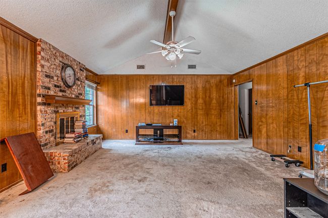 Unfurnished living room with ceiling fan, wooden walls, visible vents, carpet, and a textured ceiling | Image 20