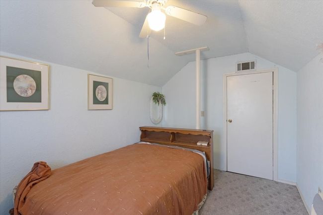 Bedroom with ceiling fan, light colored carpet, and lofted ceiling | Image 25