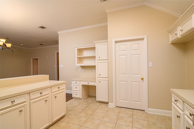 Kitchen featuring light countertops, light tile patterned floors, baseboards, crown molding, and white cabinetry | Image 8