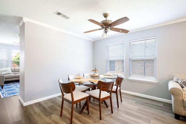 Dining room featuring a textured ceiling, a ceiling fan, wood finished floors, and crown molding | Image 4