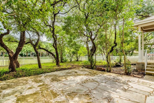 The outdoor living area features a covered patio with flagstone, along with an additional large flagstone patio—perfect for entertaining. The fenced backyard offers plenty of space and is shaded by mature trees, creating a peaceful and private retreat. | Image 22