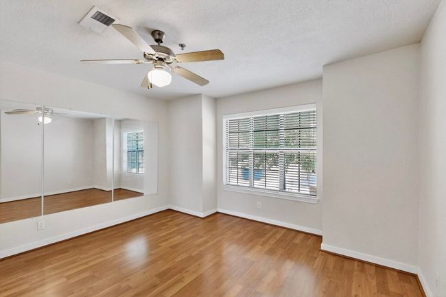 Empty room featuring plenty of natural light, a textured ceiling, light wood-style floors, and a ceiling fan | Image 7