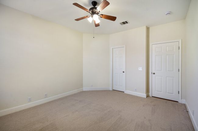 Unfurnished bedroom featuring light carpet, baseboards, and a ceiling fan | Image 13