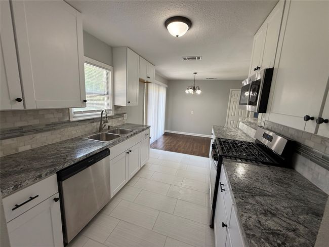 Kitchen with a sink, dishwasher backsplash, stainless steel appliances, and white cabinetry | Image 8