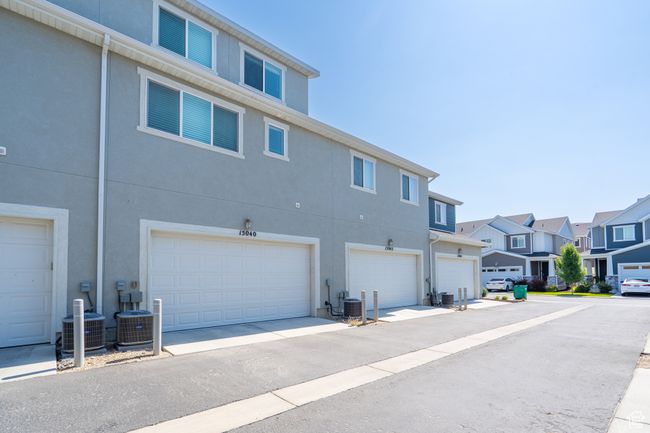 Back of property featuring stucco siding, a residential view, and a garage | Image 38