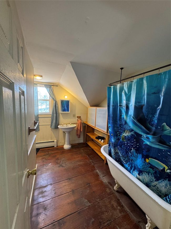 Bathroom with lofted ceiling, baseboard heating, a freestanding tub, curtained shower, and wood-type flooring | Image 26