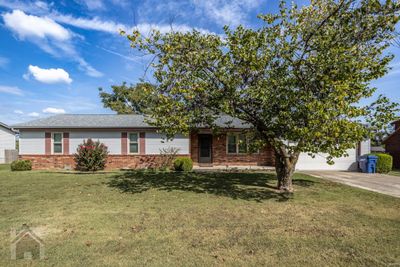 Front of house with brick trim, covered front porch, flat yard, landscaping and concrete driveway | Image 1