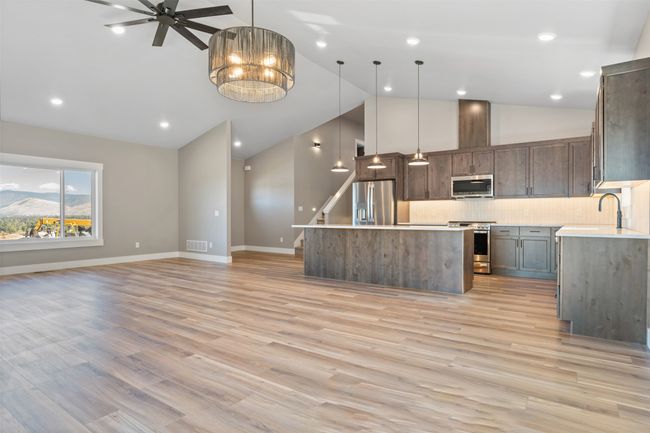 Kitchen featuring appliances with stainless steel finishes, lofted ceiling, open floor plan, a center island, and backsplash | Image 14