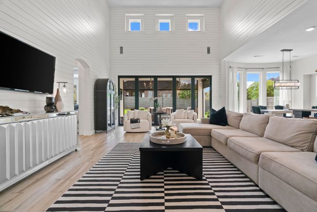 Living area with a high ceiling, light wood-style floors, healthy amount of natural light, wooden walls, and arched walkways | Image 9