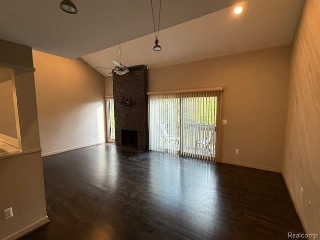 Unfurnished living room featuring dark wood finished floors, a large fireplace, and lofted ceiling | Image 9