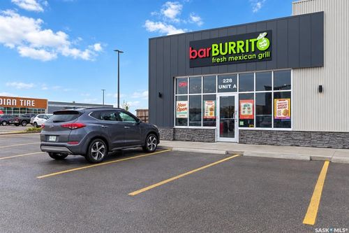 Retail storefront with floor-to-ceiling windows, dark paneled siding, and a stone veneer base | Card Image