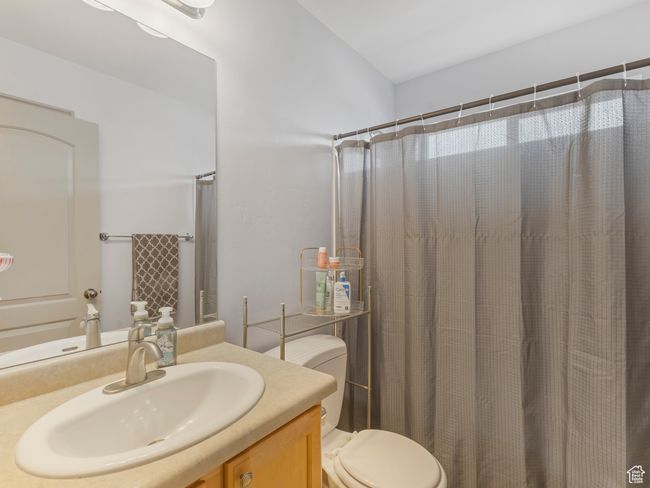 Bathroom with toilet, vanity, and curtained shower | Image 22