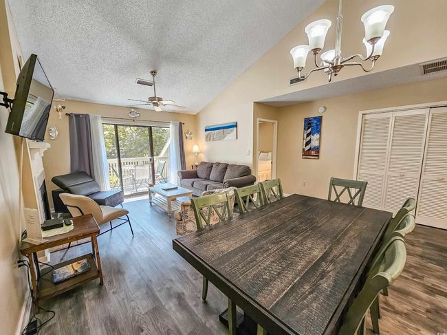Dining space featuring wood finished floors, a textured ceiling, lofted ceiling, a chandelier, and ceiling fan | Image 19