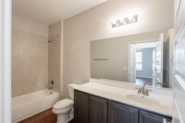 Full bath featuring vanity, wood finished floors, bathtub / shower combination, and toilet | Image 13