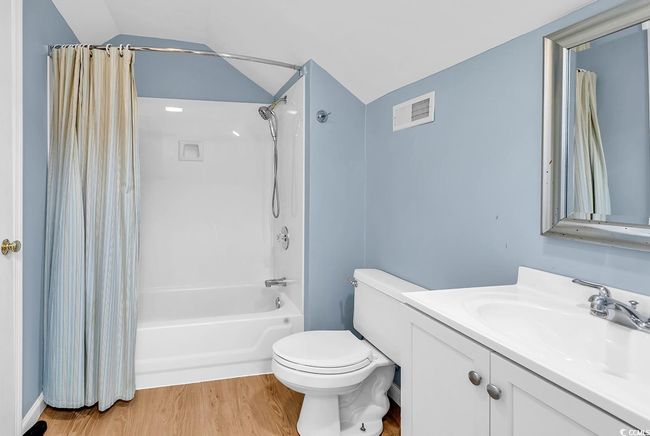 Bathroom featuring vanity, shower / bath combo, wood finished floors, and lofted ceiling | Image 29