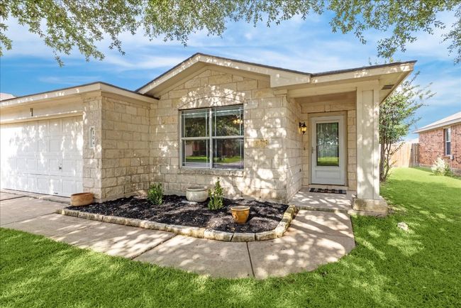 View of front entry of the home with stone siding and landscaped planter beds | Image 29