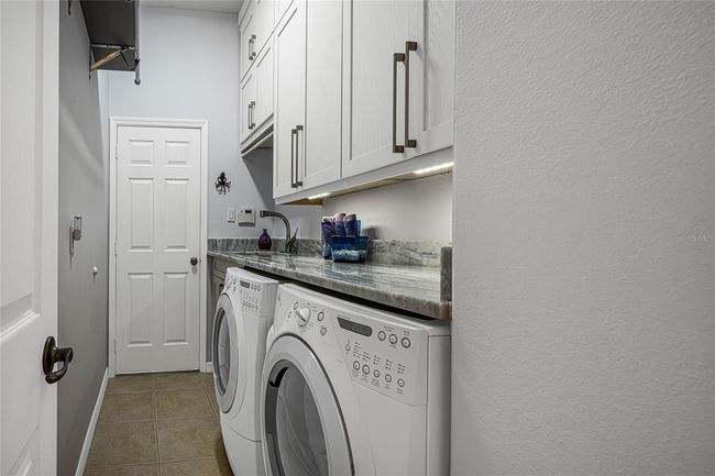 Inside Laundry with cabinetry to ceilings, deep stainless steel utility sink, and stone counters! | Image 31