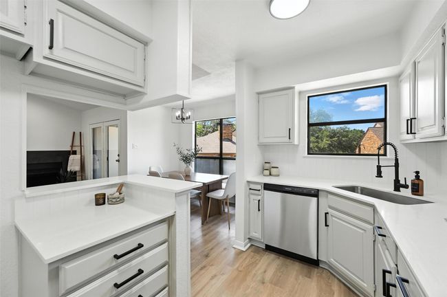 Kitchen with stainless steel dishwasher, light wood-style floors, light countertops, and a chandelier | Image 19