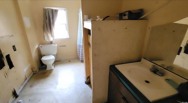 Bathroom with concrete flooring, vanity, toilet, and baseboards | Image 11