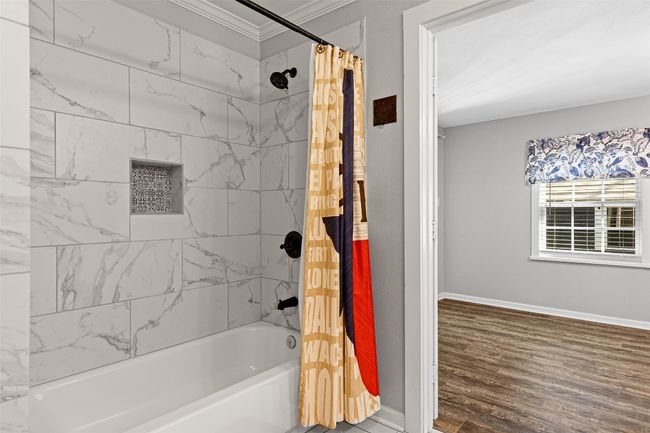 Full bath featuring shower / tub combo with curtain, crown molding, baseboards, and wood finished floors | Image 27