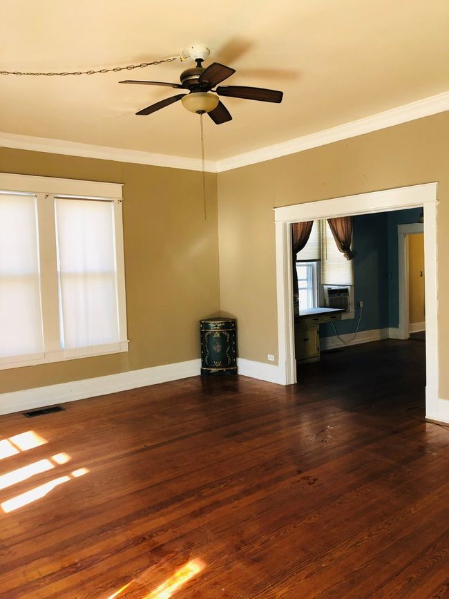 Empty room with ornamental molding, dark wood-style floors, cooling unit, and ceiling fan | Image 6