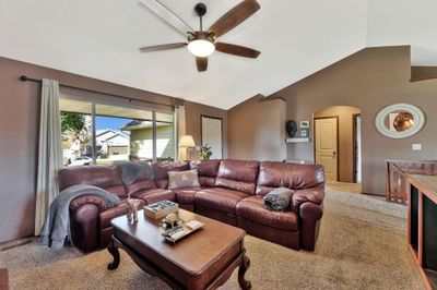 Carpeted living room with lofted ceiling and ceiling fan | Image 3