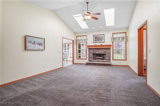 Unfurnished living room featuring a skylight, carpet, baseboards, and a fireplace | Image 18