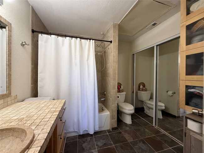 Bathroom featuring visible vents, shower / bathtub combination with curtain, toilet, vanity, and a textured ceiling | Image 15