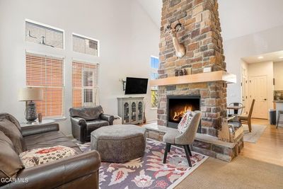 Living room featuring light wood-type flooring, a stone fireplace, and high vaulted ceiling | Image 1